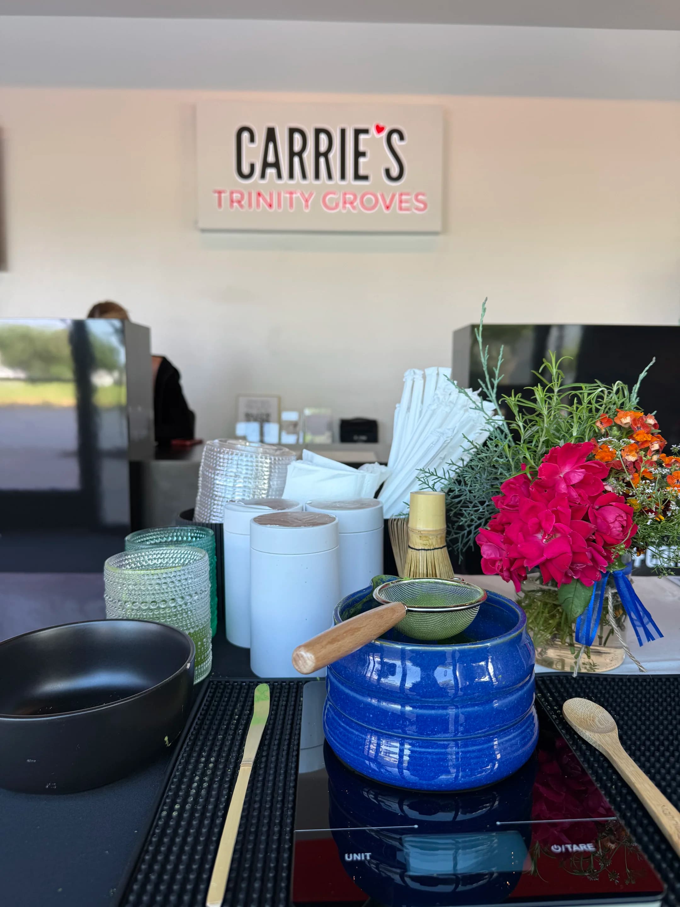 a ceremonial blue bowl with a bamboo chasen whisk and fresh herbs on a pop-up table