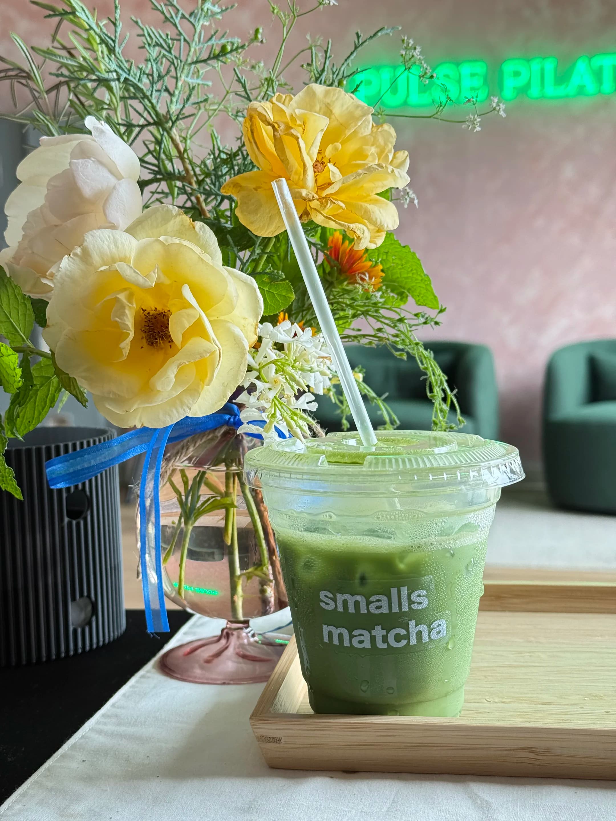 a smalls matcha drink on a wooden tray with yellow tulips beside it, at a pop-up